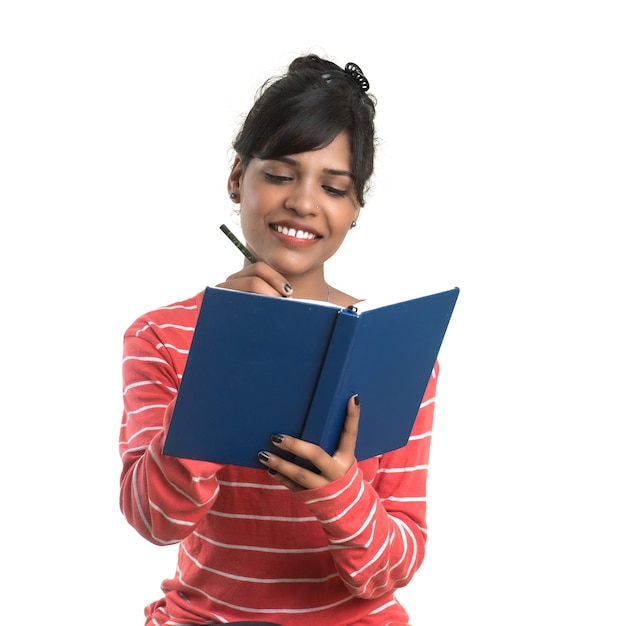 Bastante joven sosteniendo el libro y posando en la pared blanca