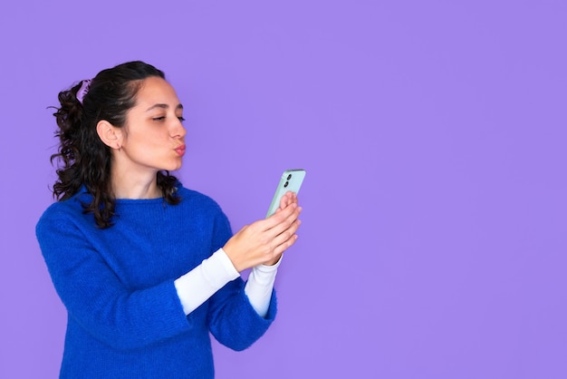 Bastante joven en suéter azul posando aislada sobre fondo morado.