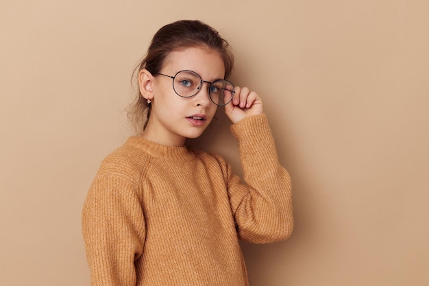 Bastante joven en un suéter y posando anteojos infancia inalterada