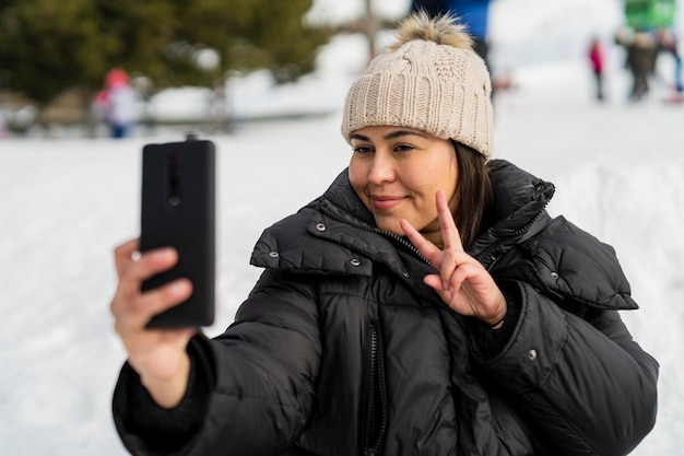 bastante joven tomando fotos en la nieve mientras disfruta