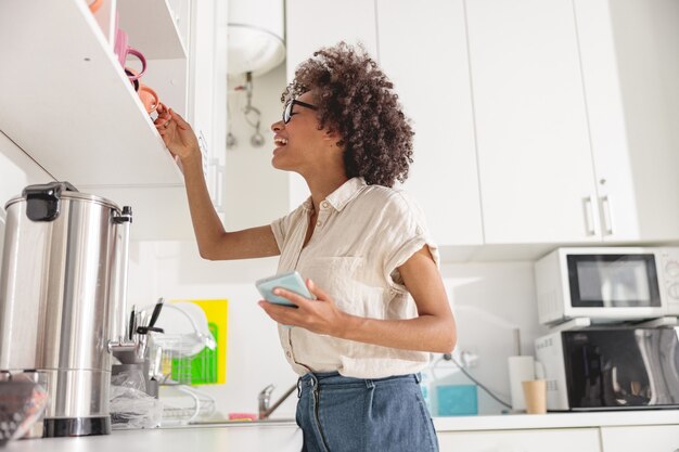 Bastante joven tomando una taza de la estantería