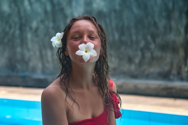 Bastante joven en traje de baño rojo relajándose en la piscina descansando un día soleado de verano