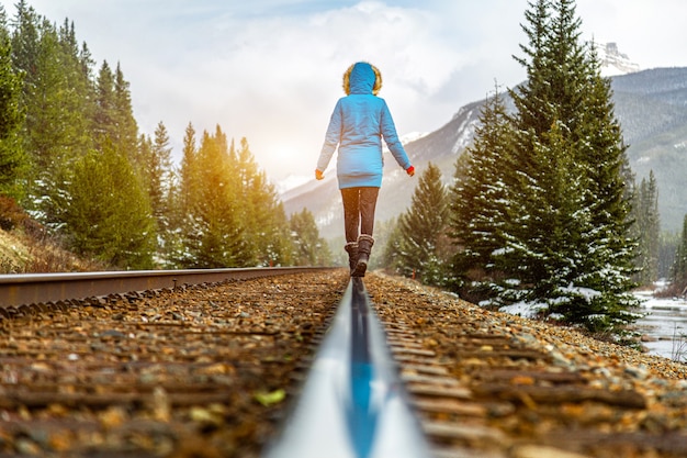 Bastante joven viajero mujer caminando sobre ferrocarril bajo la nieve Aventura en las montañas canadienses