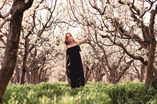 Bastante jovencita caminando en el huerto de peras con vestido negro