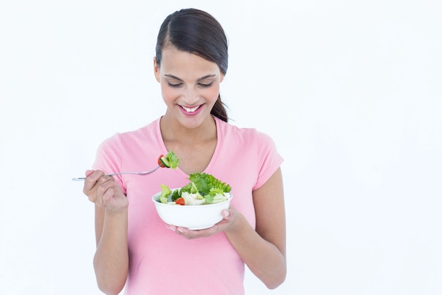 Bastante morena comiendo tazón de ensalada