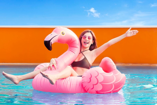 bastante, mujer joven, sentado, en, inflable, flamingo