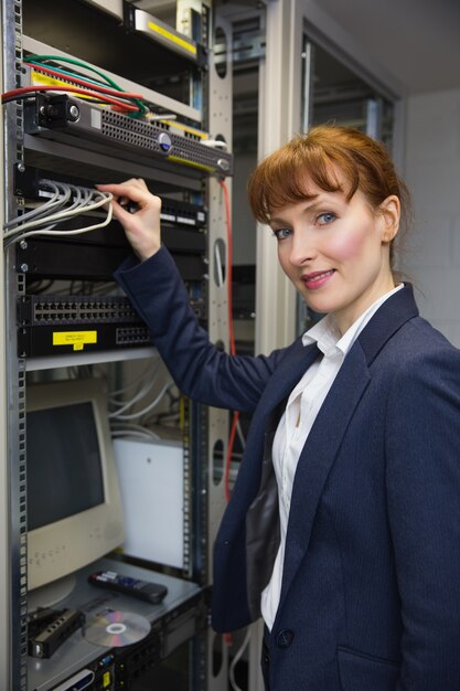 Bastante técnico informático sonriendo a la cámara mientras se fija el servidor