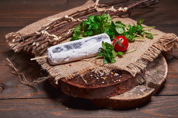 Bastelkäse mit Kirschtomaten und Kräutern auf einem Holzblockhaus