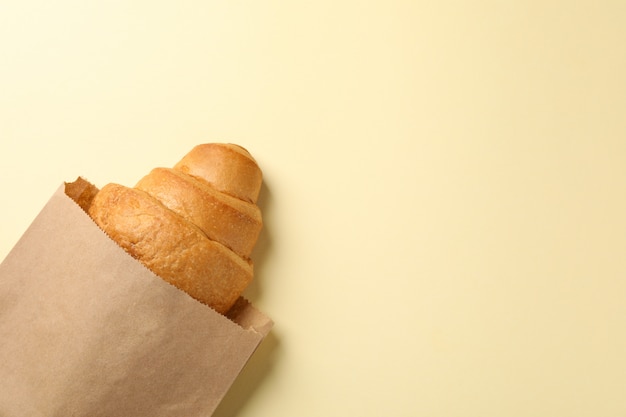 Basteln Sie Papiertüte mit Croissant auf beigem Hintergrund, Platz für Text