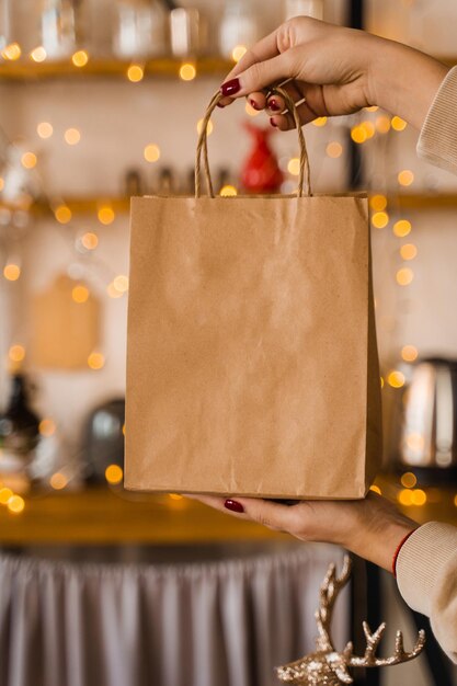 Basteltasche zum Einkaufen an Silvester. Tasche auf Weihnachtsbeleuchtung Hintergrund. Neujahrsverkauf. Vertikales Foto für soziale.