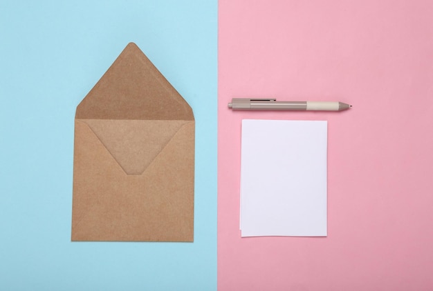 Bastelumschlag mit Brief und Stift auf blauem, rosafarbenem, pastellfarbenem Hintergrund Draufsicht