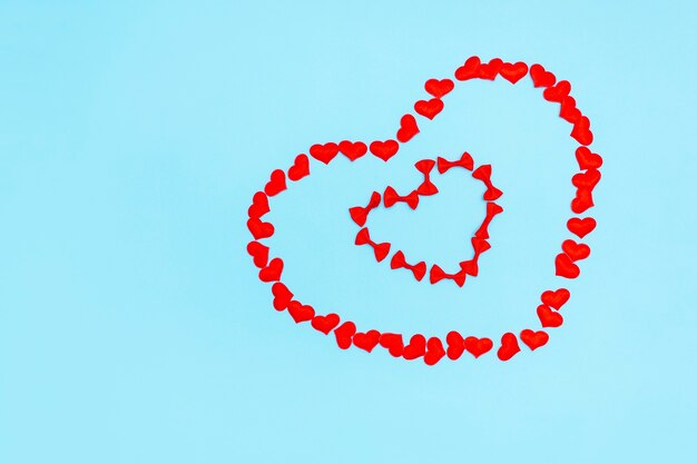 Bastidor en forma de corazón de confeti y arcos sobre una superficie azul