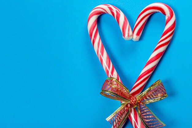 Foto bastões de doces de natal em forma de coração em fundo azul