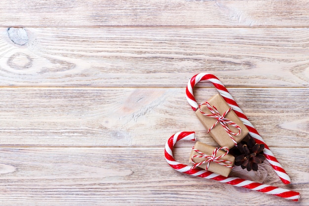 Bastões de doces e presente de Natal em fundo de madeira marrom