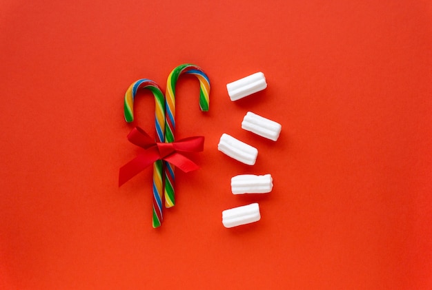 Bastões de pirulito de Natal com laço e marshmallow em um vermelho