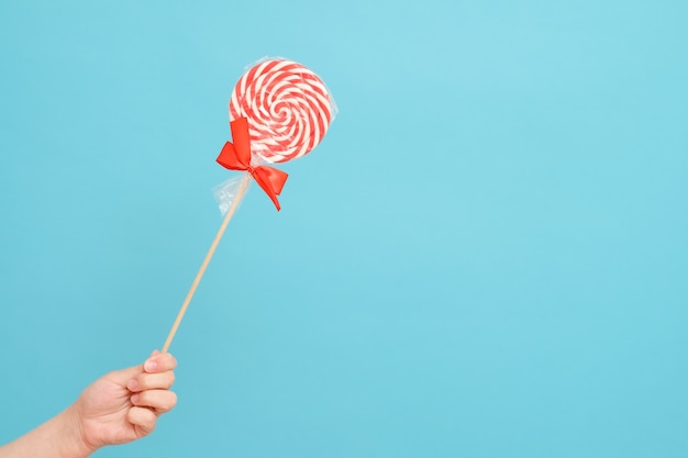 Foto bastón de caramelo en la mano aislado en azul