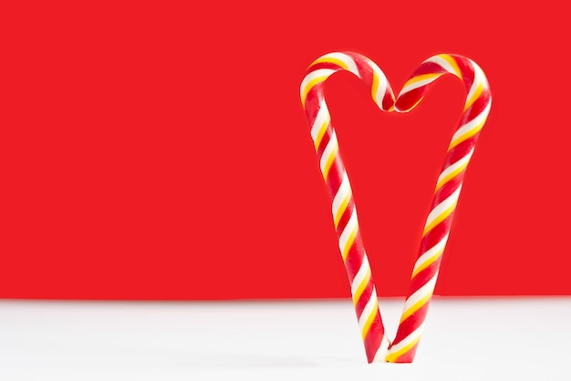 Bastones de caramelo de Navidad sobre un fondo rojo Corazón sobre un fondo rojo Corazón hecho de piruletas Corazón para el día de san valentín