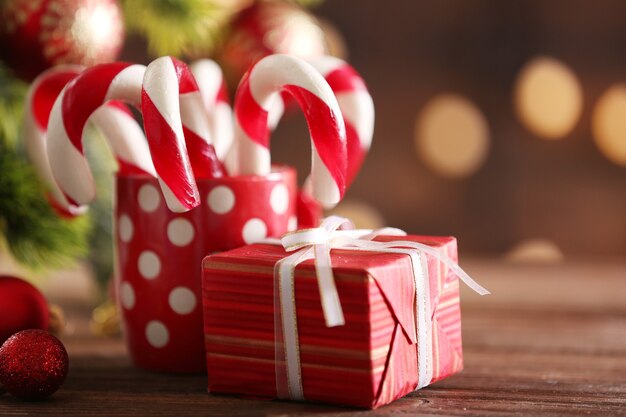 Bastones de caramelo de Navidad en taza con decoración navideña en la mesa