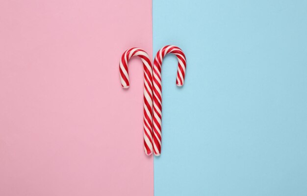 Bastones de caramelo a rayas de Navidad sobre un fondo rosa azul