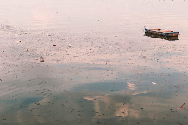 Basura y basura que flotan en la superficie con el barco viejo dispersado.