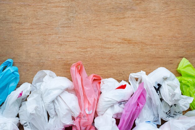 Basura plástica, las bolsas de plástico en fondo de madera.