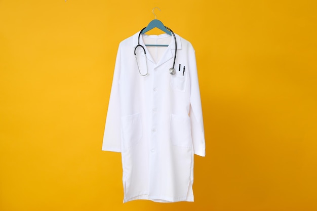 La bata blanca de un médico con un estetoscopio sobre un fondo amarillo
