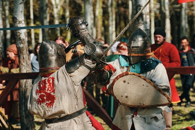 Foto batalha de cavaleiros em armadura e espadas na frente do público