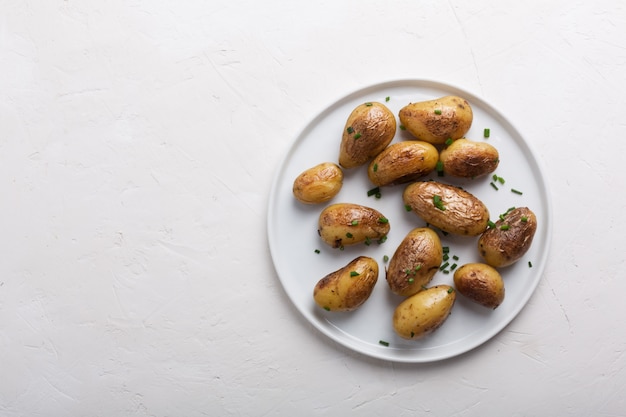 Batata al horno con cebolla verde en el plato blanco