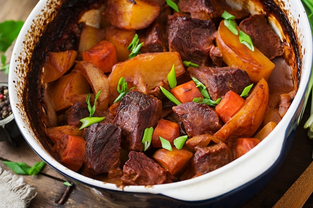 Batata assada com carne Bourguignon na velha mesa de madeira em estilo rústico