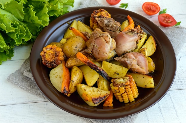 Foto batata assada com pedaços de ganso assado, legumes e grelha de milho.