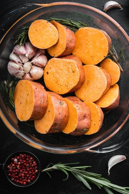 Foto batata-doce cajun para assar com ervas e especiarias em fundo preto