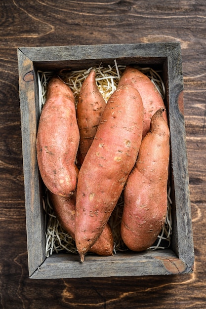 Batata-doce crua na mesa de madeira.