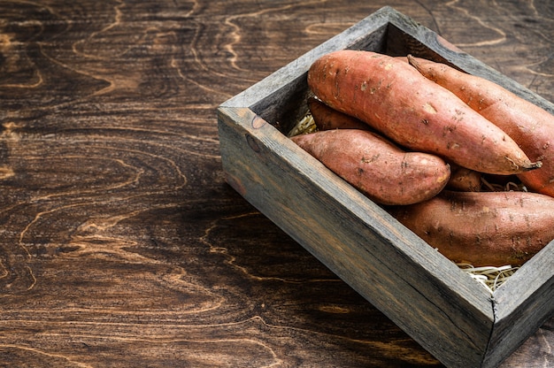 Batata-doce de batata crua na mesa de madeira.