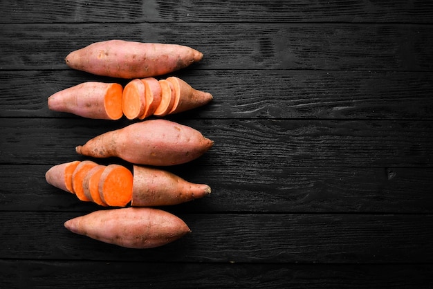 Batata doce orgânica crua em um fundo de madeira. Comida dietética. Vista do topo.