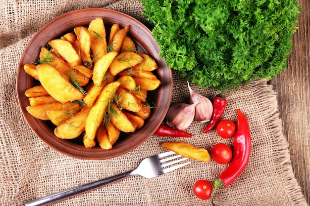 Batata frita caseira no prato guardanapo de pano de saco em fundo de madeira