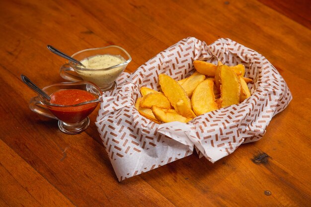 Batata frita rústica um lanche típico brasileiro servido com maionese e molho de pimenta