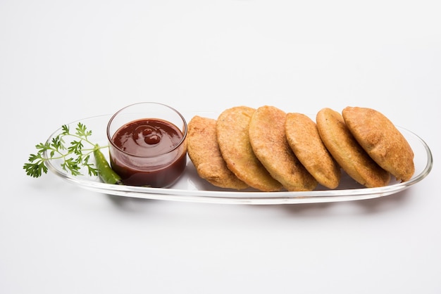 Batata ou aloo pakora ou pakode ou aloo bhajji servido com ketchup de tomate, chá verde frito frio e quente, lanche indiano popular de todos os tempos, servido sobre folha de coco fresca, foco seletivo