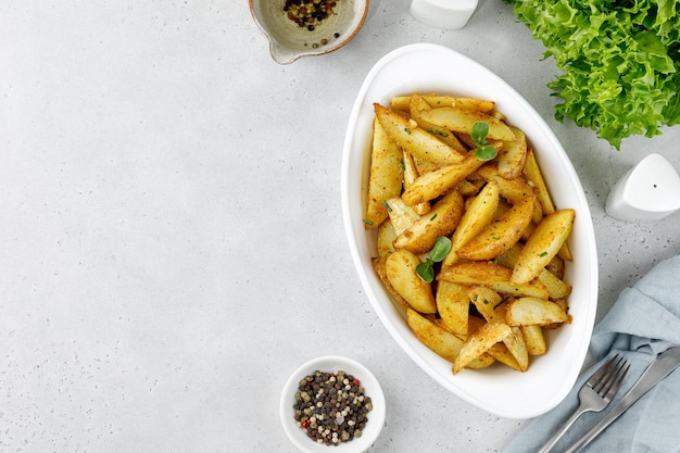 Foto batatas assadas com ervas e especiarias fatias de batata assada em assadeira branca vista superior