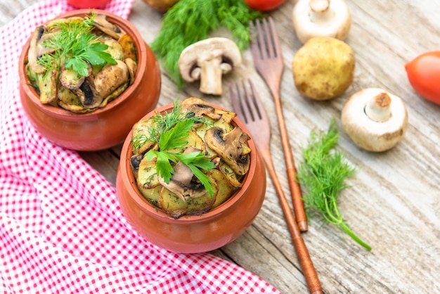 Batatas assadas com frango e cogumelos com adição de temperos diversos. em potes de barro.