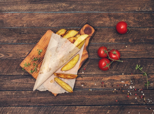 Batatas assadas com tomilho e tomate cereja em papel manteiga na tábua velha