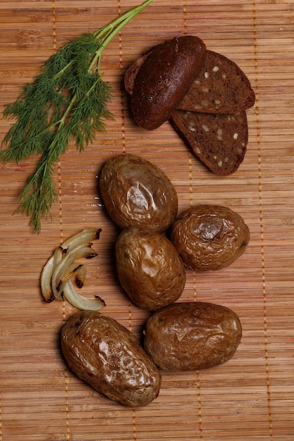 Batatas assadas e pão escuro em fundo de madeira. Comida de aldeia