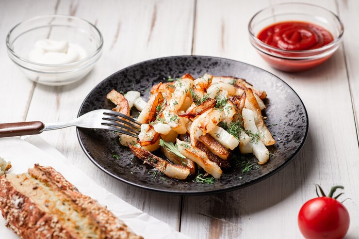 Foto batatas assadas em um fundo branco de madeira. com maionese, ketchup, tomate.