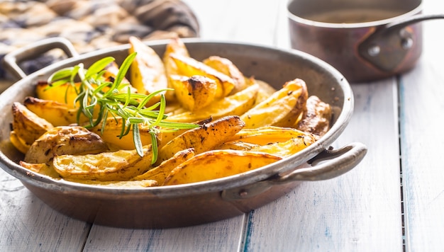 Batatas assadas em uma frigideira na placa de madeira.