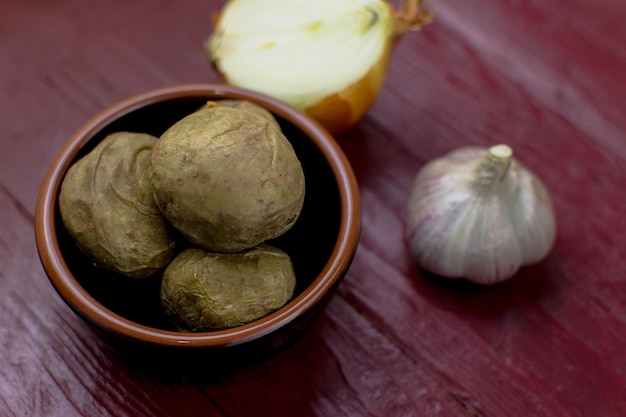 Batatas assadas inteiras em um prato sobre um fundo escuro de madeira bordô