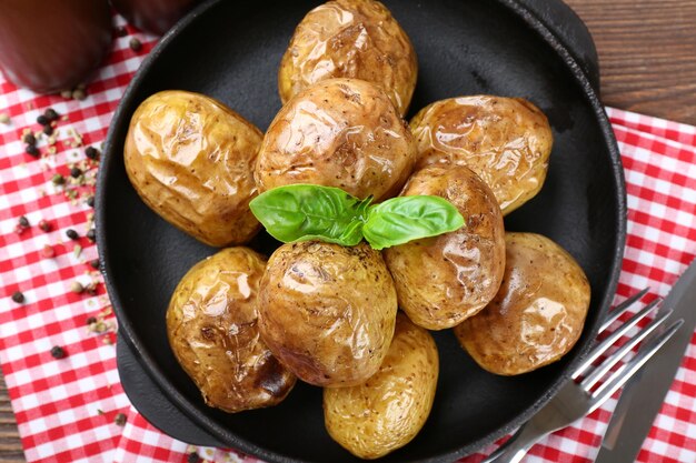 Batatas assadas na panela na mesa de madeira closeup