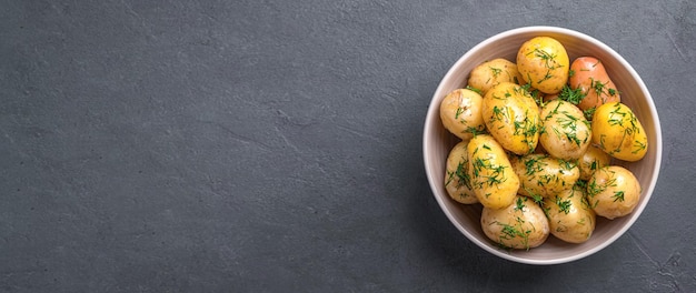 Batatas com casca cozidas com endro e manteiga em um fundo escuro