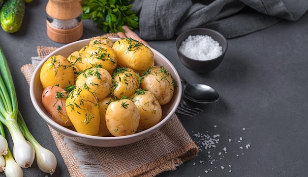 Batatas com casca jovens cozidas com endro e manteiga em um fundo escuro com endro e especiarias