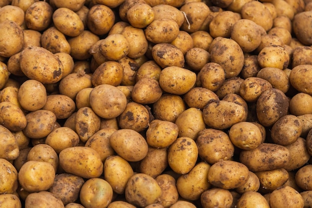 Batatas com casca marrons orgânicas frescas em um fundo de mercado fresco Textura de batata Muitos vegetais orgânicos