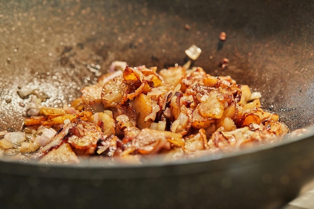 Batatas com cebola são fritas em frigideira closeup foco seletivo