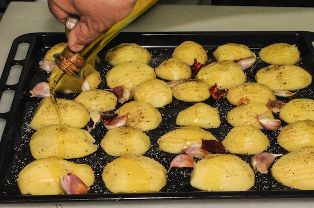 Batatas com cumes alho e azeite em uma assadeira